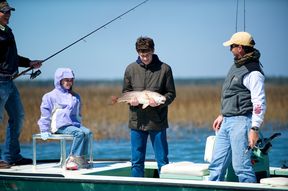 A teenage boy holds his first spot-tailed bass